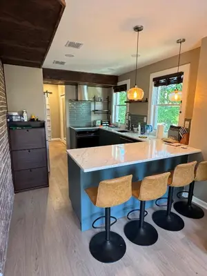 a kitchen with a large island with two bar stools at NEW! Urban Oasis, Chic 3-BR 2-BA Corner Unit, Steps Away from NYC! in Jersey City