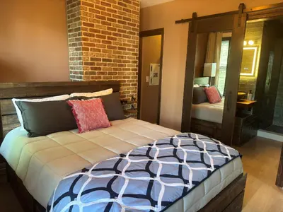 a bedroom with a large bed with a brick wall at NEW! Urban Oasis, Chic 3-BR 2-BA Corner Unit, Steps Away from NYC! in Jersey City