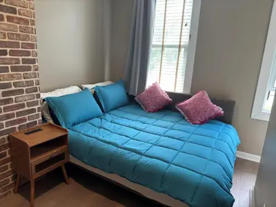 a blue couch in a room with a brick wall at NEW! Urban Oasis, Chic 3-BR 2-BA Corner Unit, Steps Away from NYC! in Jersey City