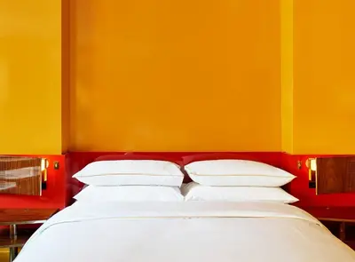 a bed with white pillows against a yellow wall at The Manner, The Unbound Collection by Hyatt in New York