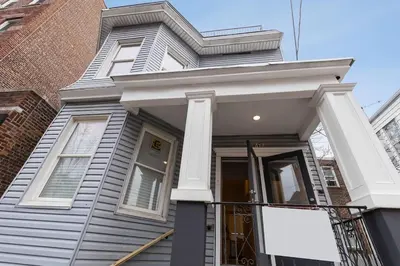 a white house with a sign in front of it at Modern & Spacious 3 BED & 2 BA Condo mins from NYC in Jersey City