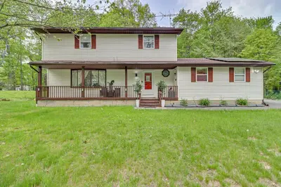 a white house with a porch and a yard at Long Pond Home with Hot Tub about 8 Mi to Kalahari! in Long Pond