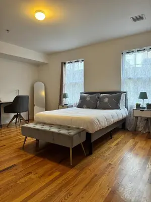 a bedroom with a large bed with a bench in it at Harmony in the Heights - Master in Newark