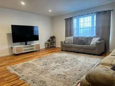 a living room with a couch and a flat screen tv at Harmony in the Heights - Master in Newark