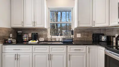 a kitchen with white cabinets and a sink and a window at Birchwood by AvantStay Game Room Lake Access in Blakeslee