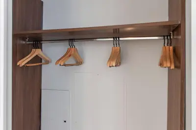 a shelf over a closet with wooden hangers at Midtown West 1br w gym wd nr bryant park NYC-1380 in New York