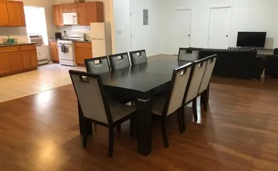 a black dining room table and chairs in a living room at Large apartment, sleeps up to 8 people comfortably, direct NYC Manhattan train only 5 minute walk away, MetLife Stadium FIFA World Cup 25 minutes away in Elizabeth