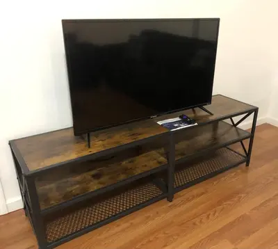 a flat screen tv sitting on top of a wooden entertainment center at Large apartment, sleeps up to 8 people comfortably, direct NYC Manhattan train only 5 minute walk away, MetLife Stadium FIFA World Cup 25 minutes away in Elizabeth