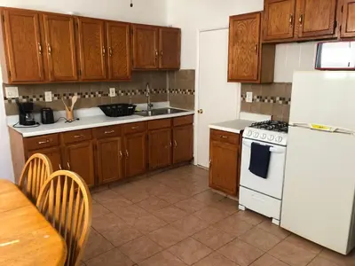 a kitchen with a white refrigerator and wooden cabinets at Private 2 bedroom and 1 bathroom house in a quiet area and convenient to NYC bus and train, MetLife Stadium FIFA World Cup 35 minutes away in Perth Amboy