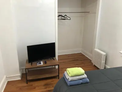 a room with a bed and a tv and a table at Private 2 bedroom and 1 bathroom house in a quiet area and convenient to NYC bus and train, MetLife Stadium FIFA World Cup 35 minutes away in Perth Amboy