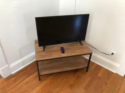 a flat screen tv on a wooden stand in a room at Private 2 bedroom and 1 bathroom house in a quiet area and convenient to NYC bus and train, MetLife Stadium FIFA World Cup 35 minutes away in Perth Amboy