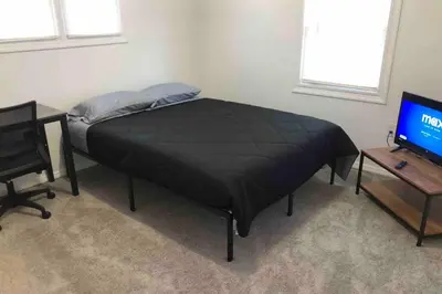 a bed in a room with a television and a table at Private 2-bedroom house, free parking, 15-min walk to direct NYC Manhattan train, MetLife Stadium FIFA World Cup 30 minutes away in Edgar