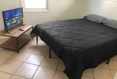 a bedroom with a bed and a table with a television at Private 2-bedroom house, free parking, 15-min walk to direct NYC Manhattan train, MetLife Stadium FIFA World Cup 30 minutes away in Edgar