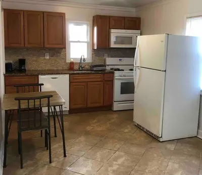 a kitchen with a white refrigerator and a table at Private 2-bedroom house, free parking, 15-min walk to direct NYC Manhattan train, MetLife Stadium FIFA World Cup 30 minutes away in Edgar