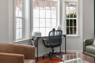 a living room with a desk and two windows at Spacious 6 BR Villa - Serene Scenic Mountain Escape in Bloomingburg