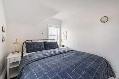 a bed in a white room with a blue blanket at Hillcrest Cottage - Charming Cottage with hot tub and view! in Obernburg