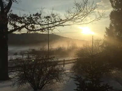 a misty sunrise on a snowy field with a fence at Hillcrest Cottage - Charming Cottage with hot tub and view! in Obernburg