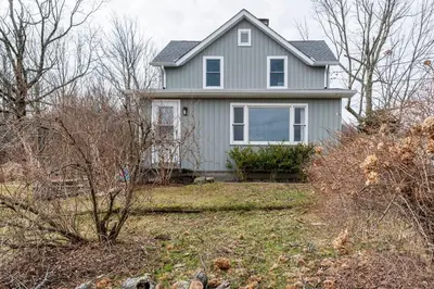 a gray house with a yard with trees at Hillcrest Cottage - Charming Cottage with hot tub and view! in Obernburg