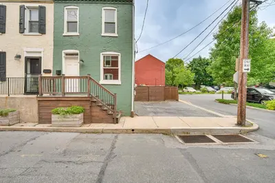 a green house with a wooden porch on a street at Chic Lancaster Vacation Rental, Walkable Location! in Lancaster
