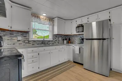 a kitchen with white cabinets and a stainless steel refrigerator at Nature Haven Pond,Pool and Hot Tub in Myerstown