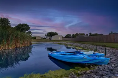 a blue boat is sitting on the water at Nature Haven Pond,Pool and Hot Tub in Myerstown