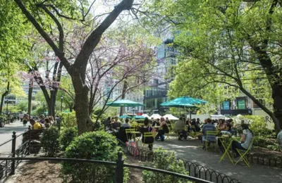 a group of people sitting at tables in a park at Lovely Room at 3 bedroom Apt at the heart of East Village in New York