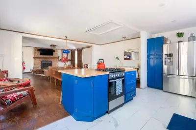 a kitchen with blue cabinets and a kitchen with a table at Serene Catskills Retreat with Deck in Woodbourne