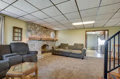 a living room with couches and a stone fireplace at Wellsboro Farmhouse with Grill and Fire Pit! in Wellsboro
