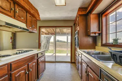 a kitchen with wooden cabinets and a sink at Wellsboro Farmhouse with Grill and Fire Pit! in Wellsboro