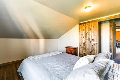 a bedroom with a bed and a wooden wall at Wellsboro Farmhouse with Grill and Fire Pit! in Wellsboro