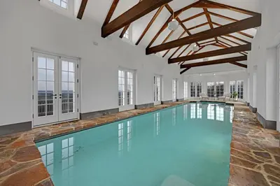 an indoor swimming pool with blue water and wooden ceilings at Roundtop Mansion-Breathtaking View, indoor Pool in Wrightsville
