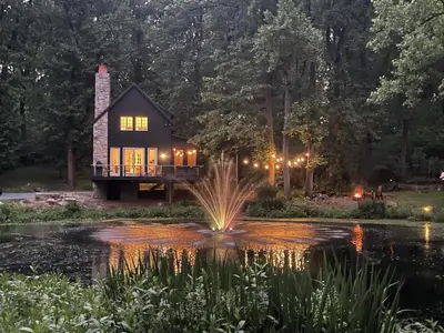 a house in the middle of a pond with a fountain at The Roundtop Chalet romantic couples getaway in Wrightsville