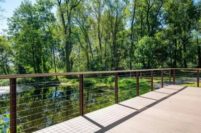 a wooden bridge over a river with trees at The Roundtop Chalet romantic couples getaway in Wrightsville