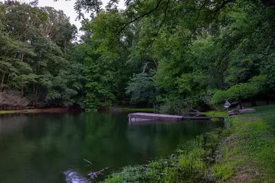 a person sitting on a bench next to a lake at Pool Cottage at Roundtop Estate couples oasis in Wrightsville