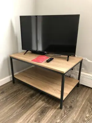 a flat screen tv on a wooden tv stand at Private 2-bedroom apartment, free parking, direct bus to NYC Manhattan only 2 blocks away, MetLife Stadium FIFA World Cup 25 minutes away in Linden