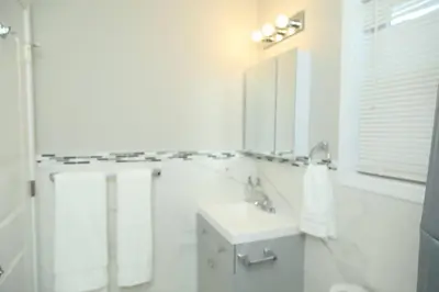 a white bathroom with a sink and a mirror at Grace Filled Apartment in Newark in Newark