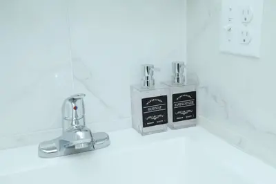 a bathroom counter with two soap dispensers on it at Grace Filled Apartment in Newark in Newark