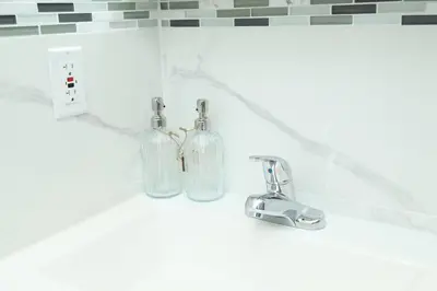 a bathroom counter with two glass bottles and a sink at Grace Filled Apartment in Newark in Newark