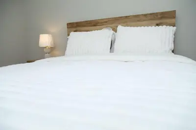 a large white bed with white sheets and pillows at Grace Filled Apartment in Newark in Newark