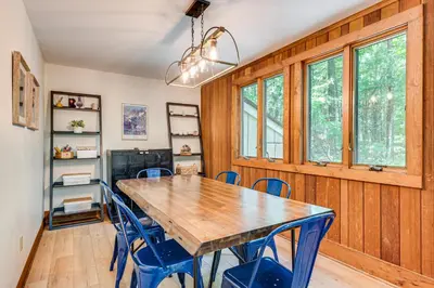 a dining room with a wooden table and blue chairs at Creek Access and Deck Family Pocono Pines Cottage in Pocono Pines