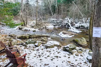 a creek with snow on the rocks and a bench at Creek Access and Deck Family Pocono Pines Cottage in Pocono Pines