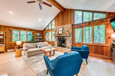 a living room with a stone fireplace and blue chairs at Creek Access and Deck Family Pocono Pines Cottage in Pocono Pines