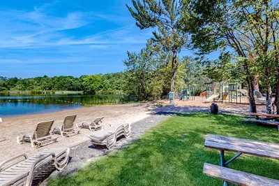 a group of chairs sitting on the grass near a lake at Pocono Waterside Escape in Tobyhanna
