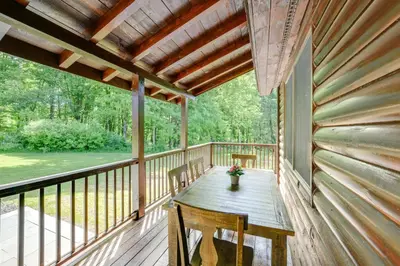 a porch with a wooden table and chairs on it at Creekside Cabin in Bainbridge with Wraparound Deck! in Sidney
