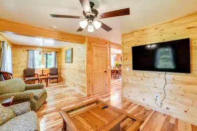 a living room with wooden walls and a flat screen tv at Creekside Cabin in Bainbridge with Wraparound Deck! in Sidney