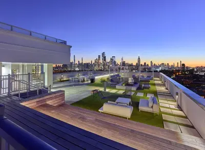 a rooftop deck with furniture and a view of the city at Empire State View - Luxury Apt - Shuttle to NYC in Hoboken