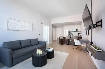 a living room with a blue couch and a kitchen at Empire State View - Luxury Apt - Shuttle to NYC in Hoboken
