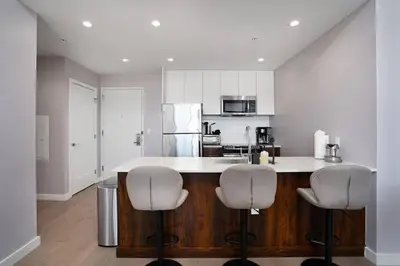 a kitchen with two white bar stools and a counter at Empire State View - Luxury Apt - Shuttle to NYC in Hoboken