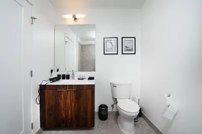 a bathroom with a toilet and a sink and a mirror at Empire State View - Luxury Apt - Shuttle to NYC in Hoboken