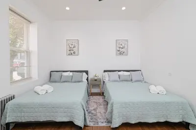 two beds in a room with white walls at 25 mins to Midtown Manhattan in Guttenberg